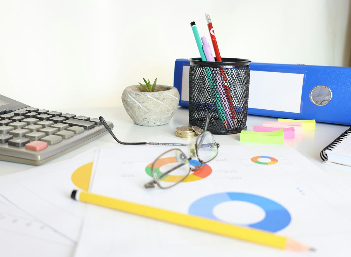 Desk with calculator, glasses, charts, and office supplies