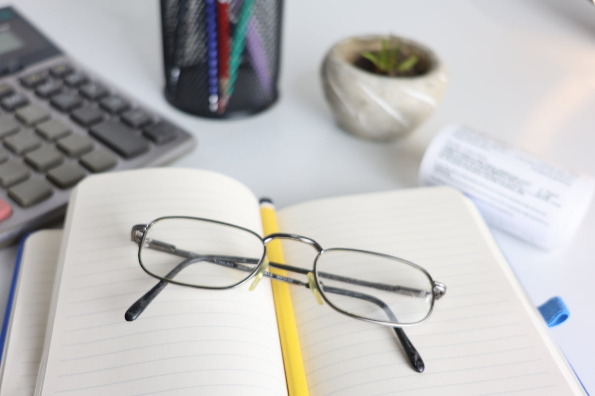 Glasses resting on an open notebook with office supplies.